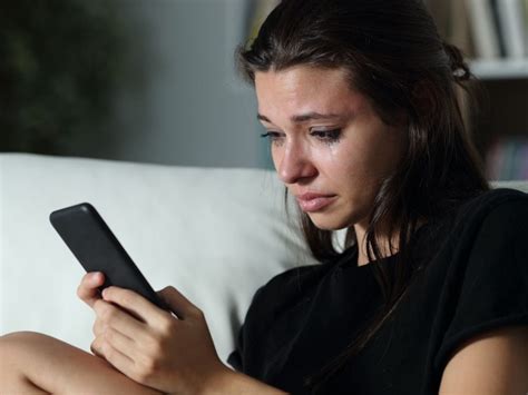 Una donna piange guardando il telefono