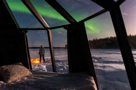 Coppia che ammira l'aurora boreale da una cabina con tetto in vetro