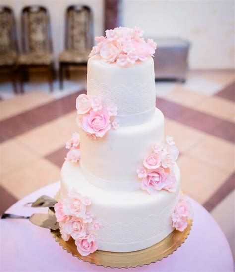 Torta nuziale bianca con fiori rosa e dettagli dorati