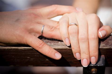 Coppia che si tiene per mano con fedi nuziali visibili