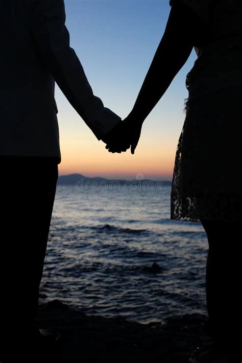 coppia che si tiene per mano durante un tramonto