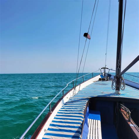 Imbarcazione a vela che naviga lungo la costa del Conero al tramonto